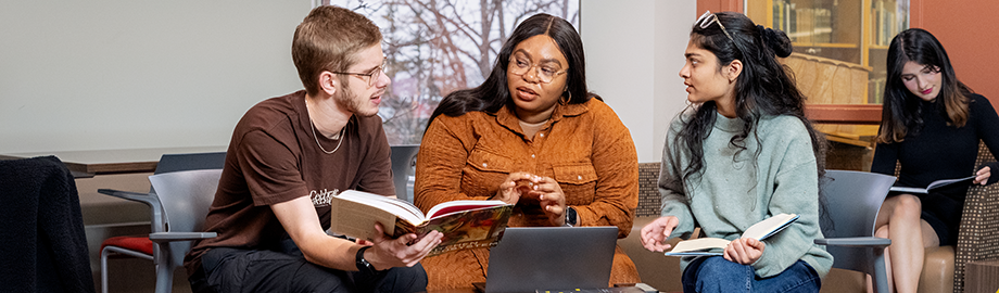 Several students sitting around a book and laptop in the MSVU Library