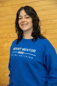 Megan is wearing a royal blue Mount Mentors Ask Me Anything long-sleeved shirt.