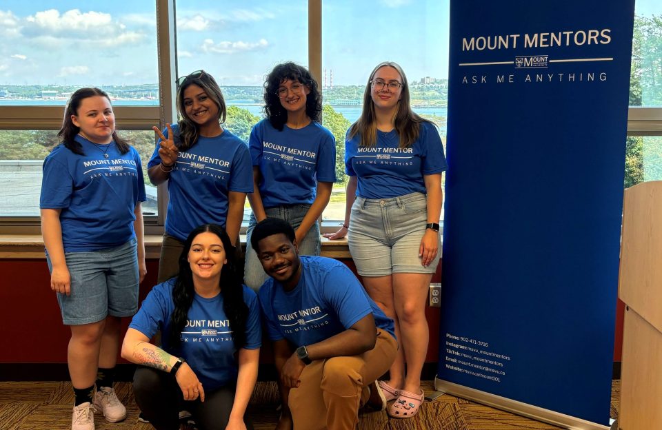 The mount mentors standing beside a banner