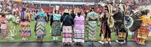 Female dancers standing in a line at a powwow.