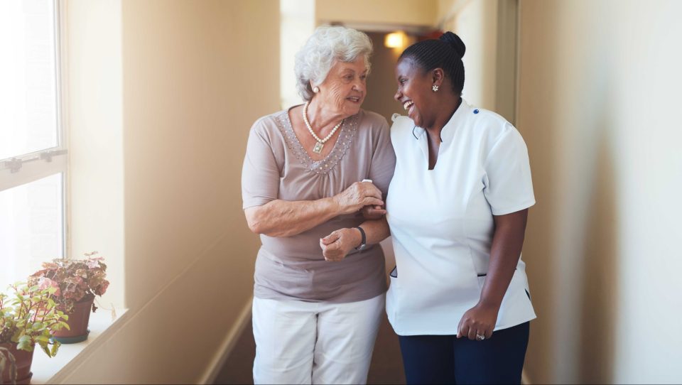 Two women walk down a hallway smiling and talking