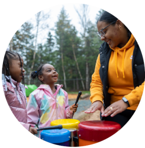 Two children playing with drums alongside an Early Childhood educator