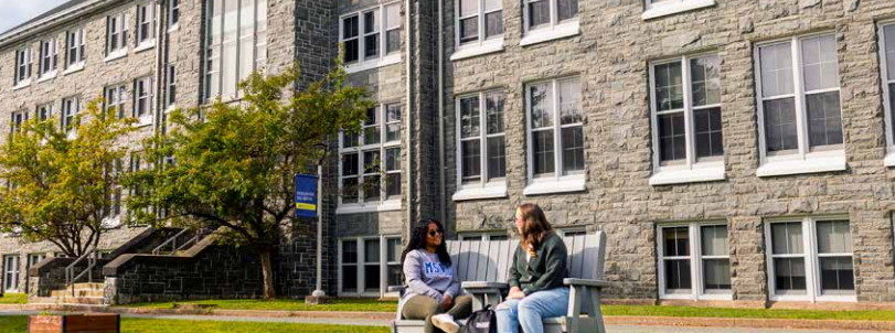 Two students sitting in chairs outside of Evaristus Hall